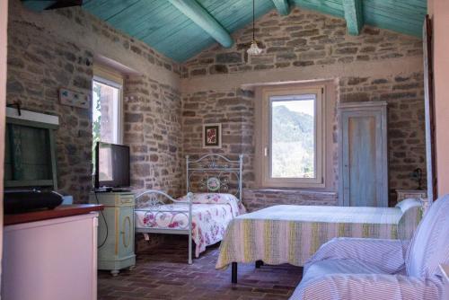 a bedroom with two beds and a tv in a room at La Locanda Della Campanara in Santa Sofia