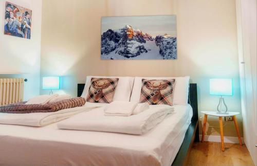 sypialnia z dużym białym łóżkiem i dwiema lampami w obiekcie DOLOMIA APARTMENTS Pinzolo w mieście Pinzolo