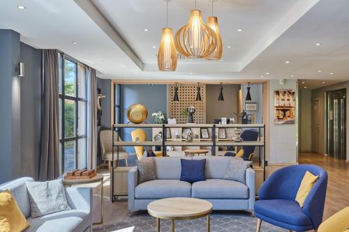 a living room with blue chairs and a couch at Appart Hotel Odalys City Aix en Provence Les Floridianes in Aix-en-Provence