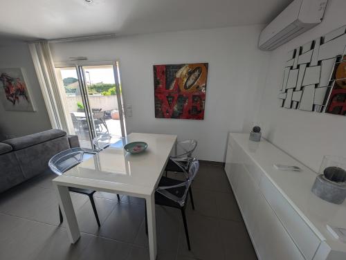 une table blanche et des chaises dans un salon dans l'établissement Villa with air-conditioned pool, 15 minutes from beaches and Montpellier, à Fabrègues