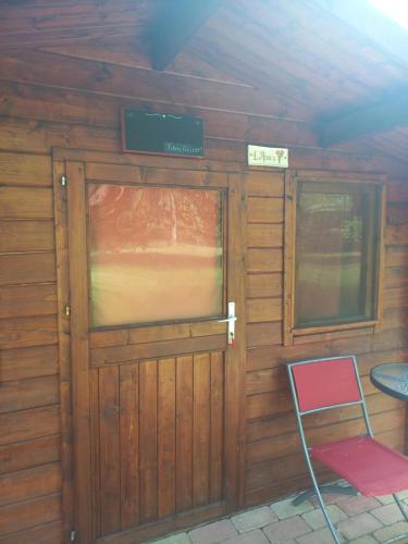 a door to a cabin with a chair and a table at Napfény Camping in Taliándörögd