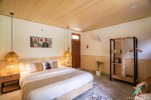 a bedroom with a large bed and a wooden ceiling at Zostel Homes Tirthan, Gushaini in Gushaini