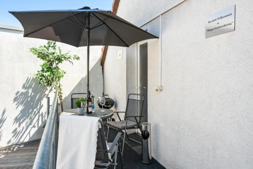 a table and chairs under an umbrella on a patio at MOLA Apartments-Moderne Ferienwohnung im Herdecker Zentrum für 3 Personen-mit Balkon-Grill-Gratis Parkplatz-WLAN in Herdecke