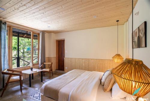 a bedroom with a large bed and a table at Zostel Homes Tirthan, Gushaini in Gushaini
