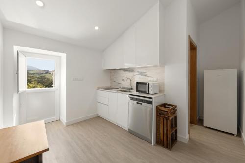 a kitchen with white cabinets and a microwave at Cavalo de Tróia Villas in Cadaval