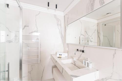une salle de bain blanche avec un lavabo et un miroir dans l'établissement GuestReady - Elegant Escape near Plaza Athénée, à Paris