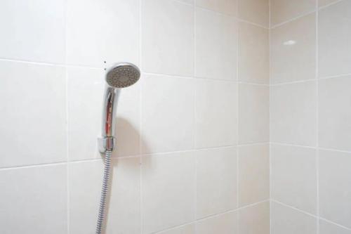 a shower with a shower head in a bathroom at RedDoorz near Mall Ratu Indah 3 in Balangberu