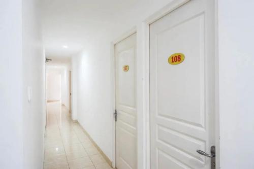 a white door with a sign on it in a hallway at RedDoorz near Mall Ratu Indah 3 in Balangberu