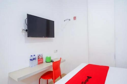 a bedroom with a bed and a tv on a wall at RedDoorz near Mall Ratu Indah 3 in Balangberu