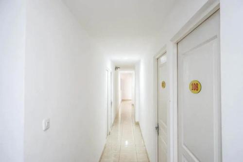 a hallway with white walls and a long corridor at RedDoorz near Mall Ratu Indah 3 in Balangberu