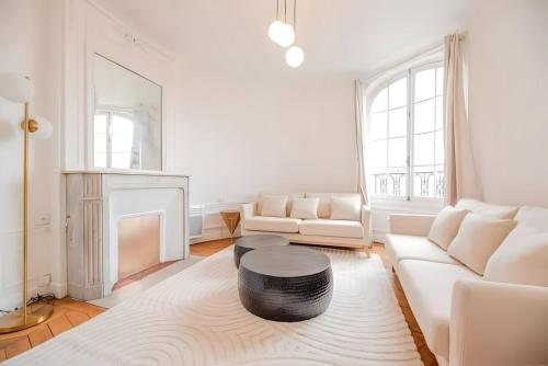 un salon blanc avec un canapé blanc et une table dans l'établissement TBS 327 - Superb apartment with Eiffel Tower view, à Paris