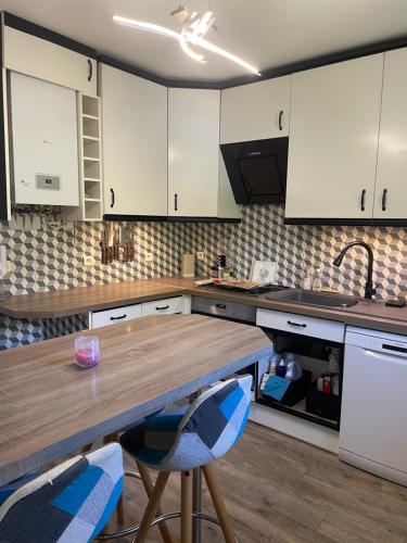 une cuisine avec des armoires blanches et une table et des chaises en bois dans l'établissement charmant appartement 3 pièces, à Mandelieu-la-Napoule