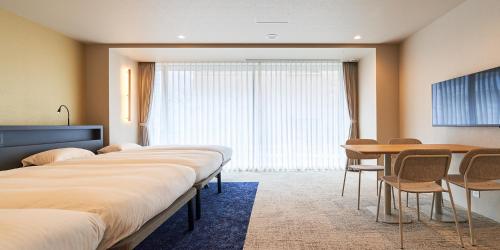 a hotel room with two beds and a table and chairs at Princess Garden Hotel in Nagoya