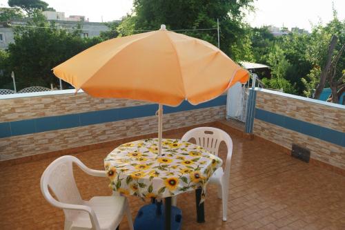 una mesa y sillas bajo una sombrilla en un techo en Azzurro Felix, en Procida