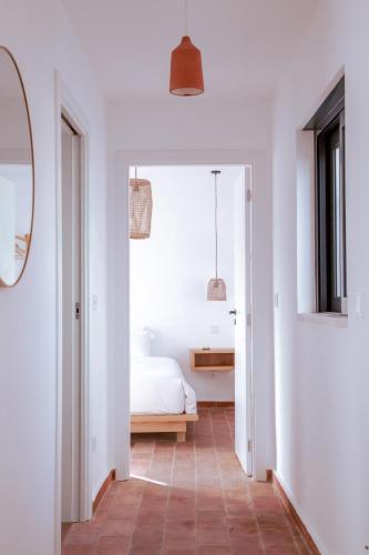 a bedroom with white walls and a bed and a mirror at Mar-Ria 7 in Fuzeta