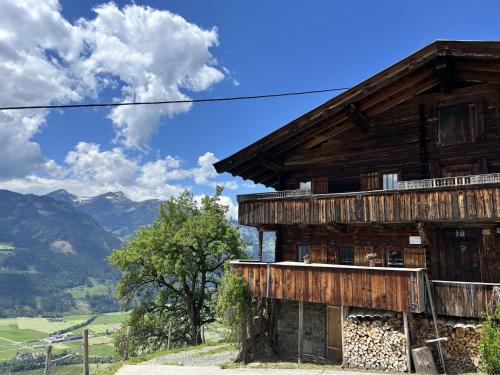 a wooden house on a hill with mountains in the background at Holiday Home Hochzillertalblick by Interhome in Gattererberg