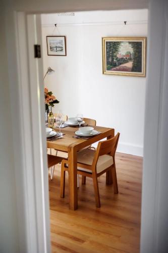 a dining room table and chairs with a wooden table and a painting at Primrose - Refurbished Family Home, With Rear Garden in Poole