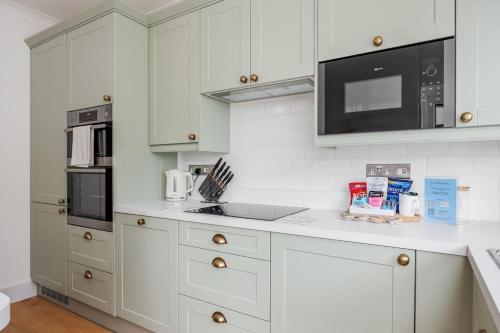 a kitchen with white cabinets and a microwave at Primrose - Refurbished Family Home, With Rear Garden in Poole