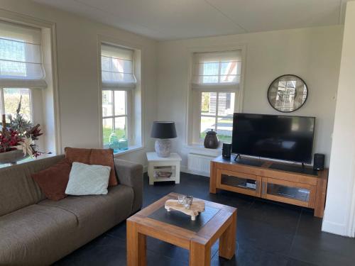 a living room with a couch and a flat screen tv at Holiday Home Wiringherlant-6 by Interhome in Noordstroe