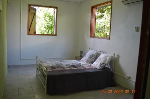 a bed in a room with two windows at Villa nana in Pointe-Noire