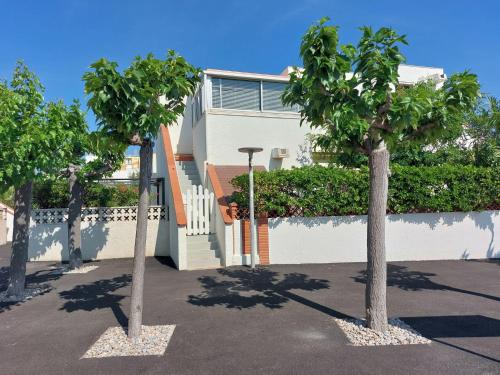 deux arbres sur un parking devant une maison dans l'établissement Studio Les Marines-4 by Interhome, au Barcarès