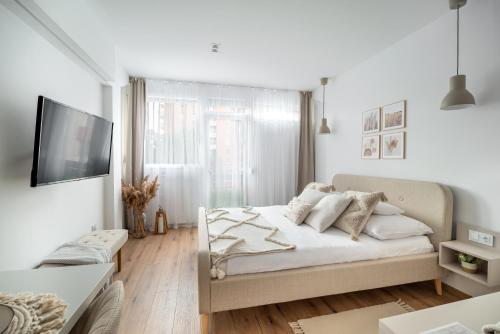 a white bedroom with a bed and a flat screen tv at Geri Harmony Home in Zalaegerszeg