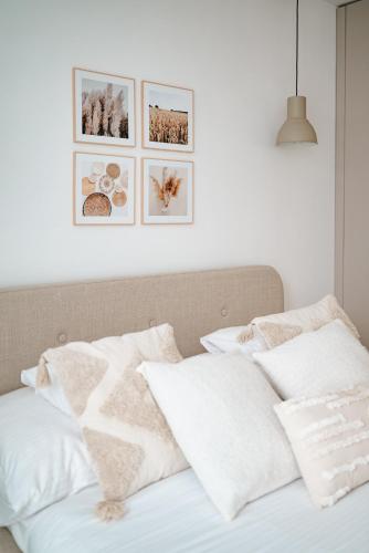 a bed with white pillows and pictures on the wall at Geri Harmony Home in Zalaegerszeg
