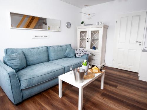 een woonkamer met een blauwe bank en een tafel bij Apartment Scholle by Interhome in Norddeich