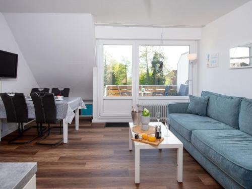 een woonkamer met een blauwe bank en een tafel bij Apartment Scholle by Interhome in Norddeich