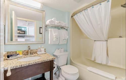 a bathroom with a toilet and a sink and a mirror at Flip Flop at Compass Cove in Myrtle Beach