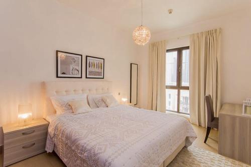 a white bedroom with a bed and a window at Cozy 1BR Apart Downtown Burj Khalifa and Dubai Mall in Dubai
