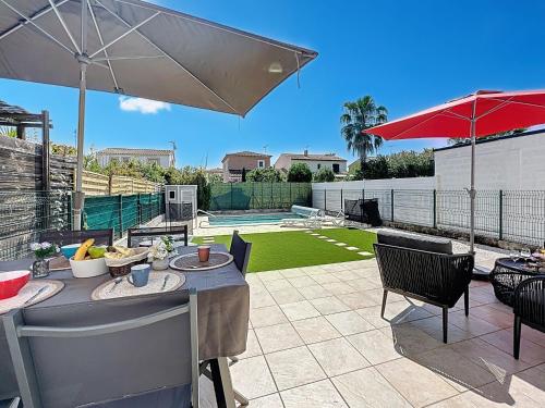 a patio with a table and chairs and an umbrella at Holiday Home Les Lauriers by Interhome in Aigues-Mortes