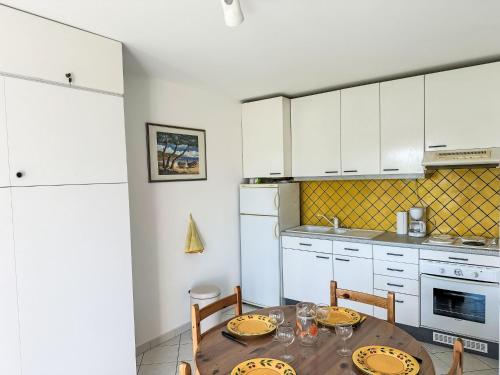 une cuisine avec une table, des chaises et des armoires blanches dans l'établissement Apartment Les Roses Lauriers by Interhome, au Lavandou