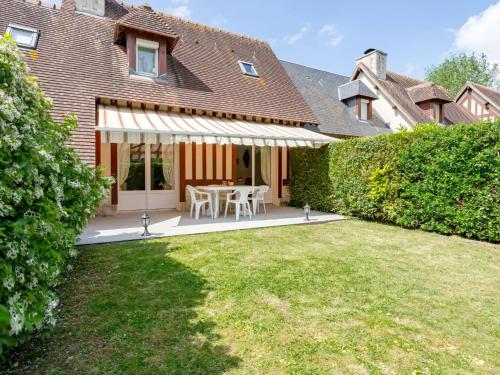 a patio with a table and chairs in a yard at Holiday Home Domaine de Clairefontaine-2 by Interhome in Deauville
