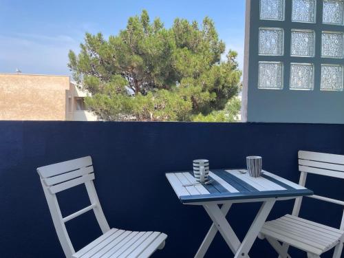une table bleue, deux chaises, une table et un arbre dans l'établissement T2 proche de la mer, à Marseille