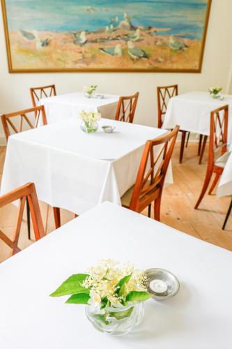 two white tables with flowers on them in a room at Lundsgaard Gods Badehotel in Kerteminde