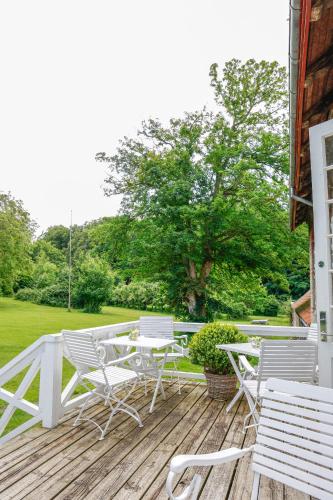 a group of white chairs and tables on a deck at Lundsgaard Gods Badehotel in Kerteminde