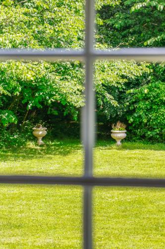 a window view of a yard with two vases in the grass at Lundsgaard Gods Badehotel in Kerteminde