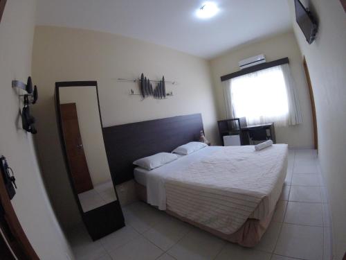 a bedroom with a large bed and a mirror at Hotel Hola in Florianópolis