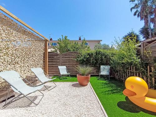 une cour arrière avec des chaises de jardin et un canard en caoutchouc géant dans l'établissement Apartment Le Saint Jean by Interhome, à Fréjus