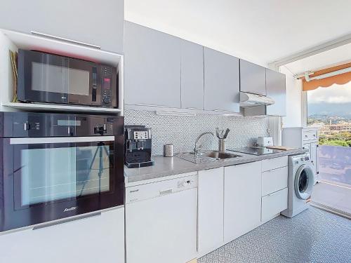 une cuisine blanche avec un évier et un micro-ondes dans l'établissement Apartment Le Bonaparte-2 by Interhome, à Roquebrune-Cap-Martin
