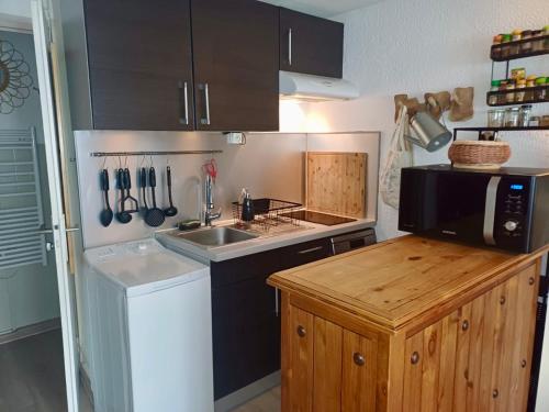 une petite cuisine avec un évier et un micro-ondes dans l'établissement Escapades Bohème - 3 pers - Histoire de Clés, au Cap d'Agde