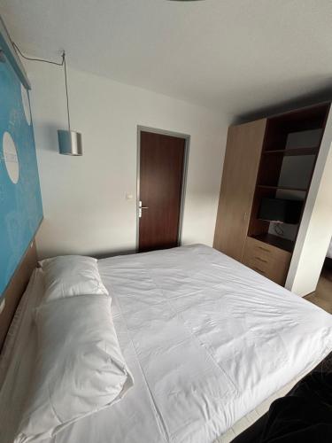 a bedroom with a large white bed with a wooden cabinet at ibis Styles Bethune Bruay la Buissière in Bruay-la-Buissiere