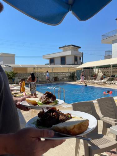a person holding two plates of food next to a swimming pool at Teras in Seferihisar
