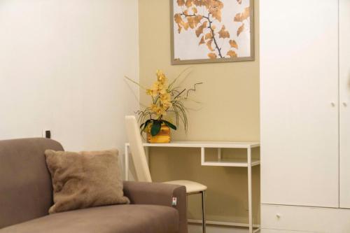 un salon avec une chaise et une table avec une plante dans l'établissement DOLOMIA APARTMENTS PINZOLO vicino alle funivie, à Pinzolo