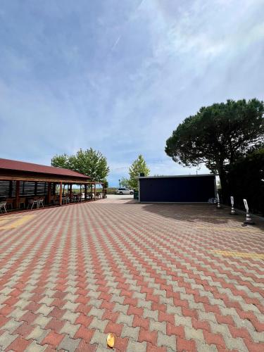 a large patio with a building and a tree at Kamberi Hotel & Apartments in Velipojë