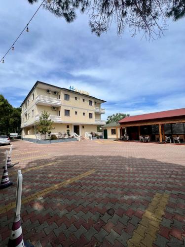 a large building with a brick courtyard in front of it at Kamberi Hotel & Apartments in Velipojë