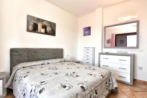 a bedroom with a bed and a dresser and a mirror at Perla Apartment con vista mare in Olbia