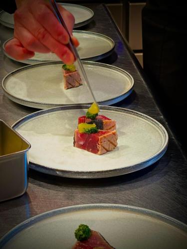 a person cutting a piece of food on a plate at 白水温泉竹の倉山荘 in Minami Aso