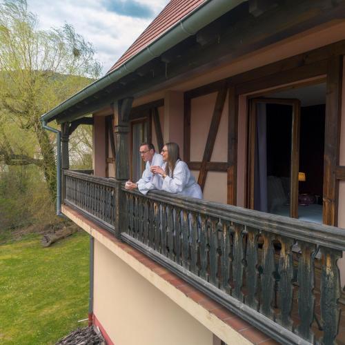 two people sitting on a balcony of a house at Hôtel Restaurant Verger des Châteaux, Route des vins Haut-Koenigsbourg in Dieffenthal